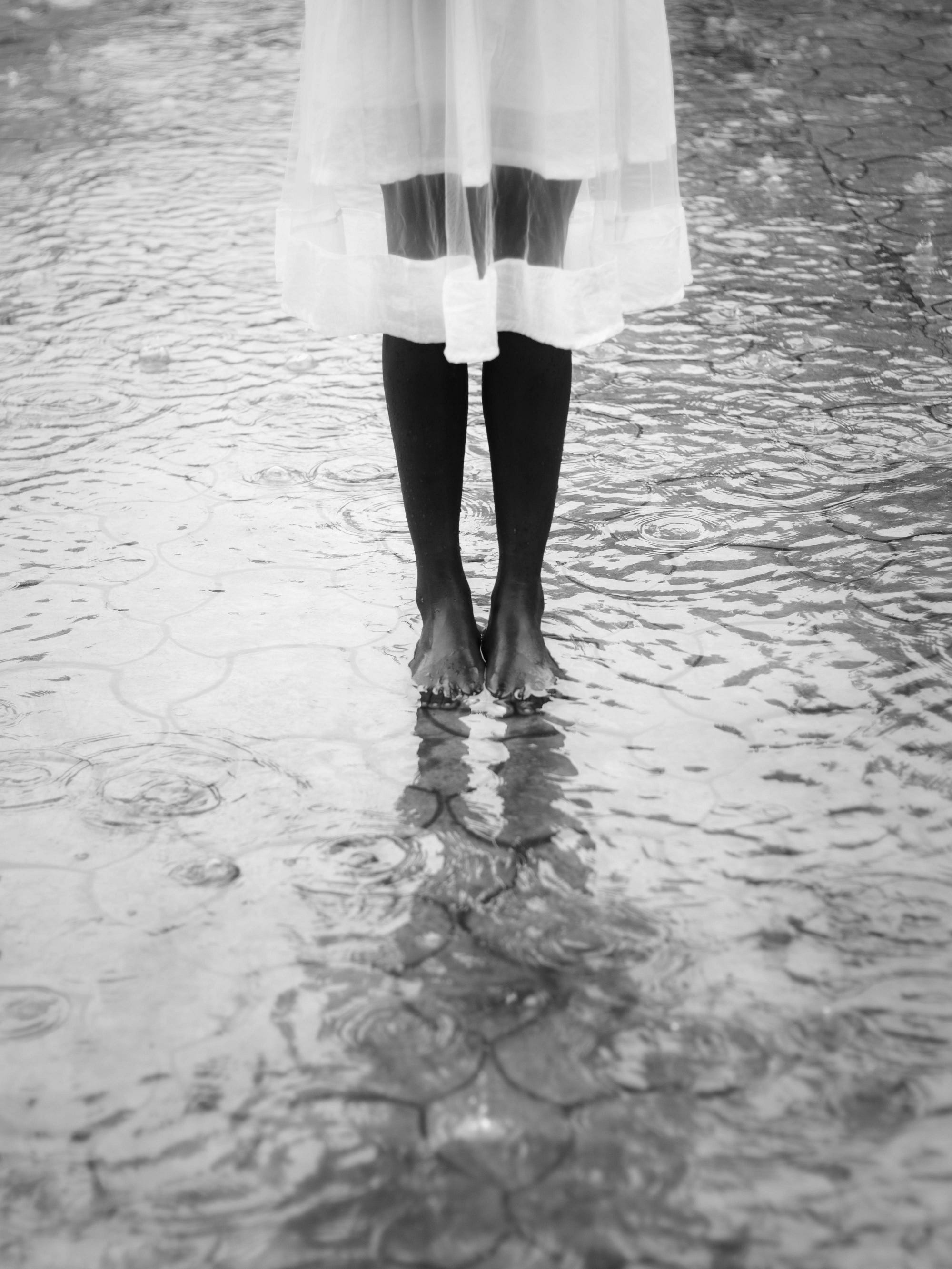 A barefoot woman standing in still water, evoking emotional clarity, the calm after choosing herself, and the quiet strength of honoring personal boundaries.